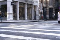 a woman wearing white and holding an umbrella crossing the street in front of a macy store