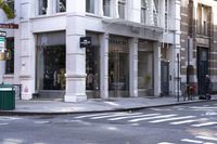 a woman wearing white and holding an umbrella crossing the street in front of a macy store