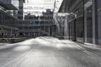 an empty city street with glass windows and people walking down the sidewalk near a tall building