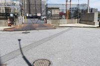 the empty urban street has some metal structures on the side of it, including a fire hydrant and manholed access