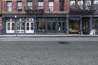 a very small shop and a huge building on the side of the road a big dark grey fire hydrant