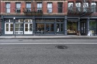 a very small shop and a huge building on the side of the road a big dark grey fire hydrant