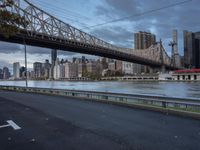 an elevated bridge crosses over the water on a cloudy day in new york city, with the empire and river bridges visible