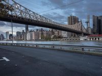 an elevated bridge crosses over the water on a cloudy day in new york city, with the empire and river bridges visible