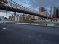 an elevated bridge crosses over the water on a cloudy day in new york city, with the empire and river bridges visible