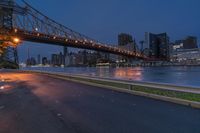 an empty road on a city street near the water at night, with streetlights glowing down