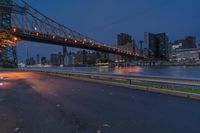 an empty road on a city street near the water at night, with streetlights glowing down