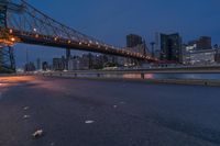 an empty road on a city street near the water at night, with streetlights glowing down