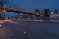 an empty road on a city street near the water at night, with streetlights glowing down