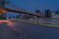 an empty road on a city street near the water at night, with streetlights glowing down