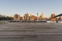 the view of a city is over the river, and the boat dock has benches and boats