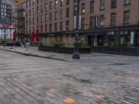 the city street has a couple of old buildings along it and tables and umbrellas in front of it