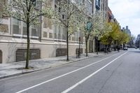 the sidewalk in front of a building with trees growing outside of it is empty,