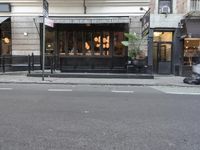 a black shopfront with a black fence and white painted streetside and trees on either side