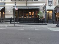 a black shopfront with a black fence and white painted streetside and trees on either side