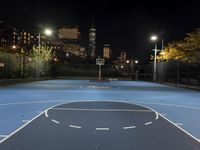 a basketball court with a city in the background at night time, with a half moon behind it