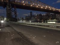 an empty road on a city street near the water at night, with streetlights glowing down