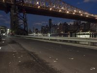an empty road on a city street near the water at night, with streetlights glowing down