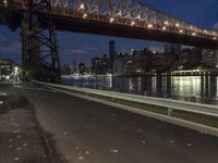 an empty road on a city street near the water at night, with streetlights glowing down