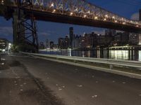 an empty road on a city street near the water at night, with streetlights glowing down