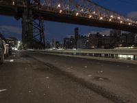 an empty road on a city street near the water at night, with streetlights glowing down
