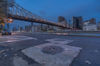 an empty road on a city street near the water at night, with streetlights glowing down