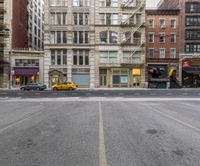 an empty parking lot with taxi waiting at a stoplight in a city near other buildings