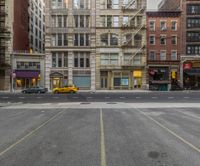 an empty parking lot with taxi waiting at a stoplight in a city near other buildings