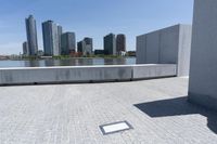a shadow in the concrete by a city canal and a large city skyline in the distance