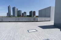 a shadow in the concrete by a city canal and a large city skyline in the distance