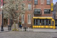 a yellow restaurant with a awning on the sidewalk in front of it and a building behind it