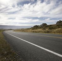 a motorcycle is parked on the side of a road near the grass and rock formations