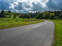 the asphalt road is winding towards a small town on a hillside overlooking a vast field