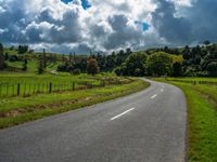 the asphalt road is winding towards a small town on a hillside overlooking a vast field