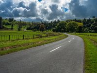 the asphalt road is winding towards a small town on a hillside overlooking a vast field