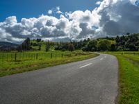 the asphalt road is winding towards a small town on a hillside overlooking a vast field