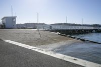 the boardwalk is leading towards the water to a pier next to some boats on the beach