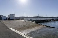 the boardwalk is leading towards the water to a pier next to some boats on the beach