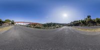 a very long curved highway by some trees and a bridge over a hill with a blue sky