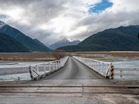 the view of mountains on the mountain range from a bridge at a train station in new zealand