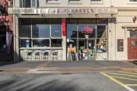 a small grocery store on the corner of a street between two tall buildings in front