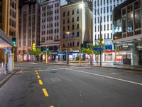 the night time image of an empty city street with buildings and pedestrians on it, which are not in the center of the photo