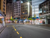 the night time image of an empty city street with buildings and pedestrians on it, which are not in the center of the photo