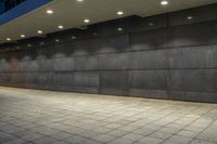 a black stone wall lit up by lighting at night with low lighting on the floor