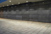 a black stone wall lit up by lighting at night with low lighting on the floor