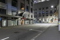 empty street on the corner with buildings and an awning over it at night with lights shining on all over the city