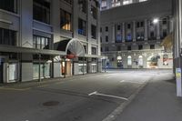 empty street on the corner with buildings and an awning over it at night with lights shining on all over the city