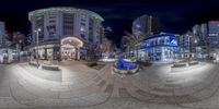 fisheye shot of a plaza that is in a city at night time, from an angle