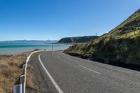 road near water, and hills on both sides of road in front of the ocean