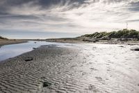 an empty beach with a small body of water near the shore with some rocks in it